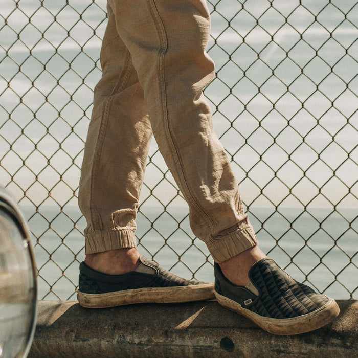 fit model standing on a roadside railing in The Apres Pant in Khaki Double Cloth