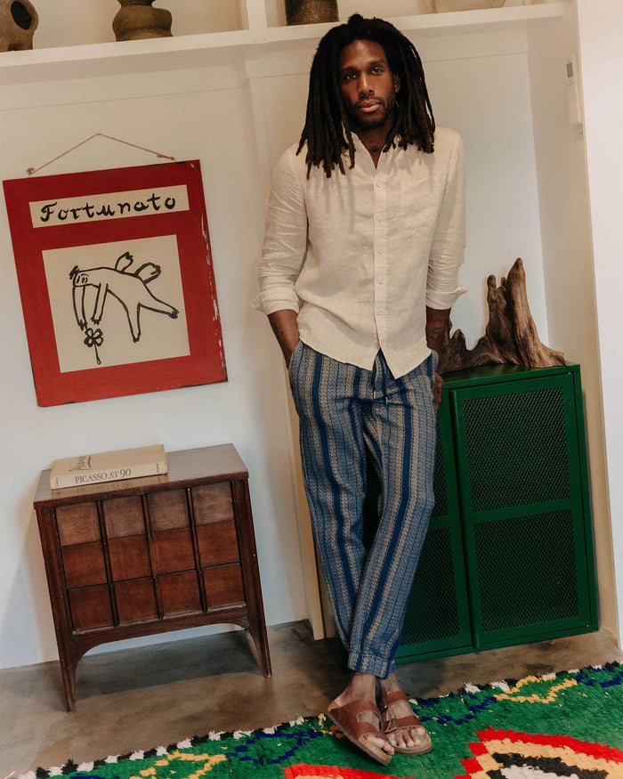 fit model leaning against the wall wearing The Apres Pant in Marine Stripe