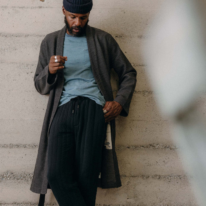 fit model leaning against the wall wearing The Apres Robe in Charcoal Sashiko