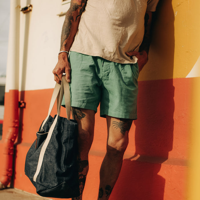 fit model leaning against an orange wall in The Après Short in Ocean Pinwale