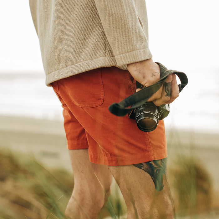 fit model wearing The Après Short in Rust Pinwale and holding a camera