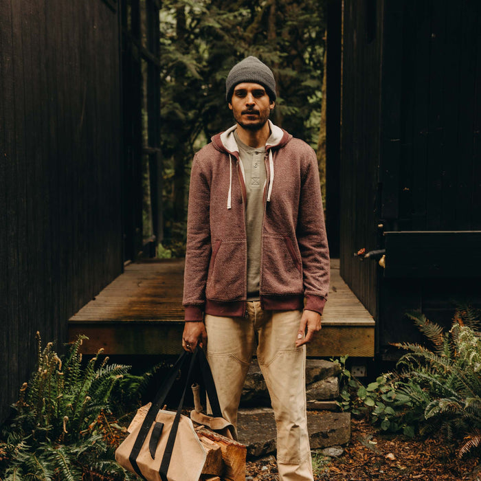 fit model posing in front of a house wearing The Apres Zip Hoodie in Merlot French Terry Twill