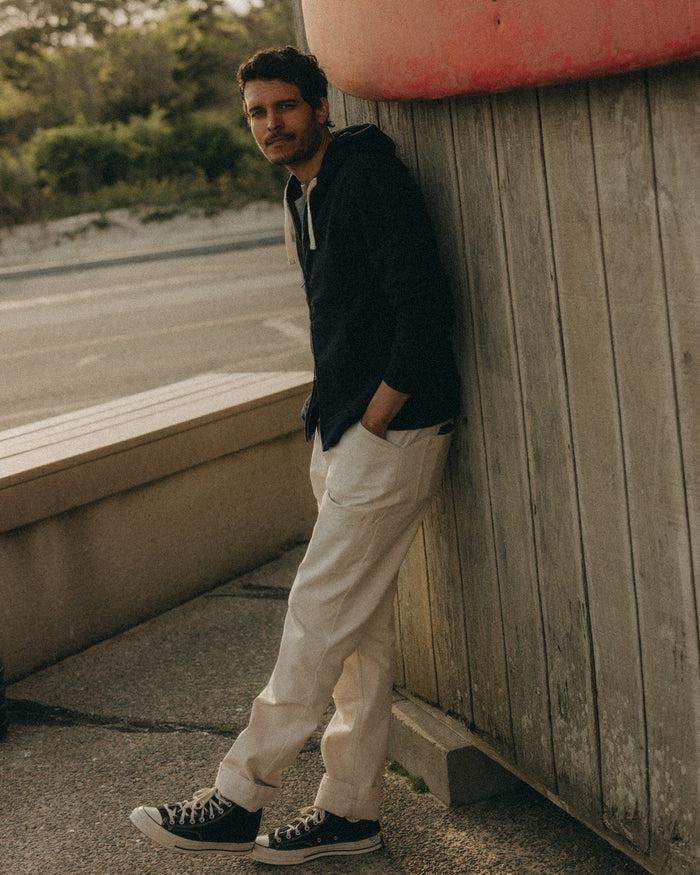 fit model leaning against the wall wearing The Apres Zip Hoodie in Rinsed Indigo Terry