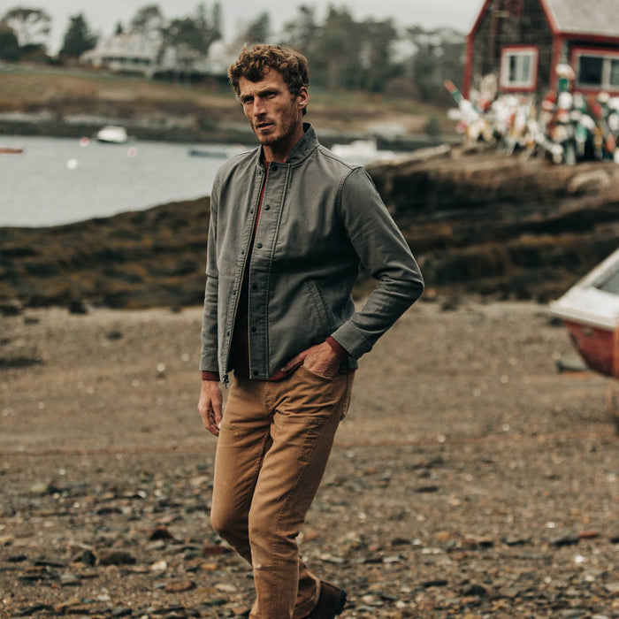 fit model wearing The Bomber Jacket in Charcoal Jungle Cloth, walking on beach