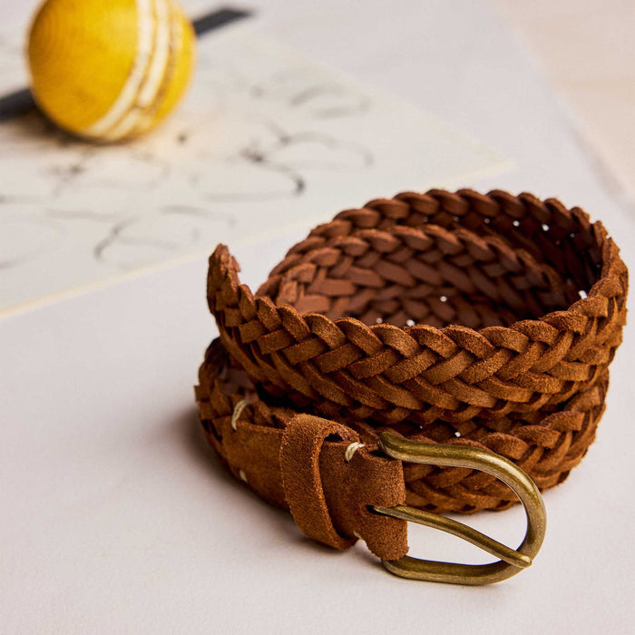 editorial image of The Braided Belt in Tan Suede rolled up next to a ball