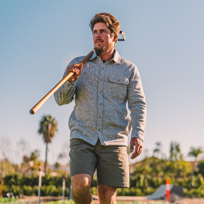 fit model wearing The Breaker Overshirt in Ash while holding a garden hoe