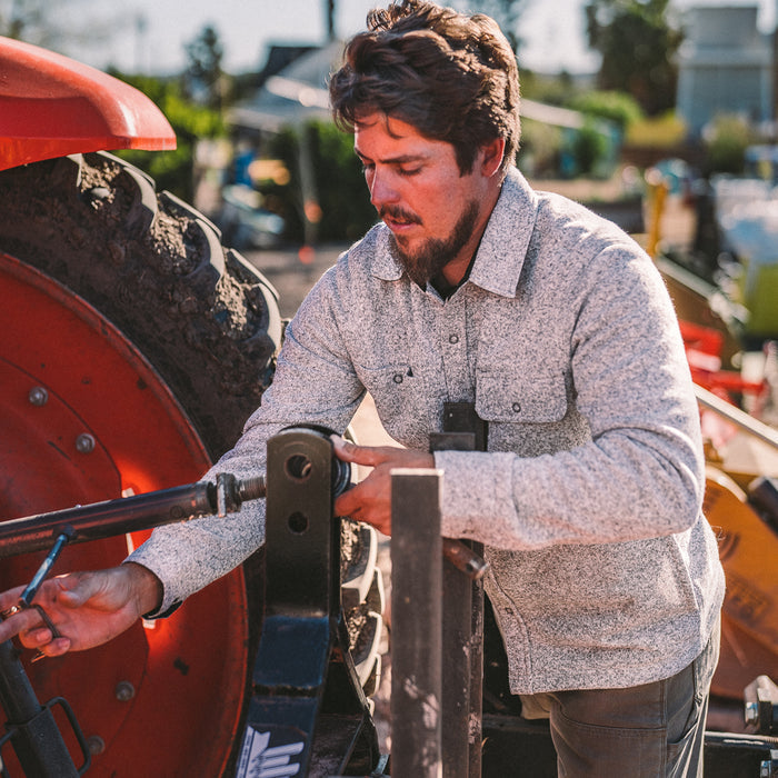 fit model wearing The Breaker Overshirt in Ash while changing a tire