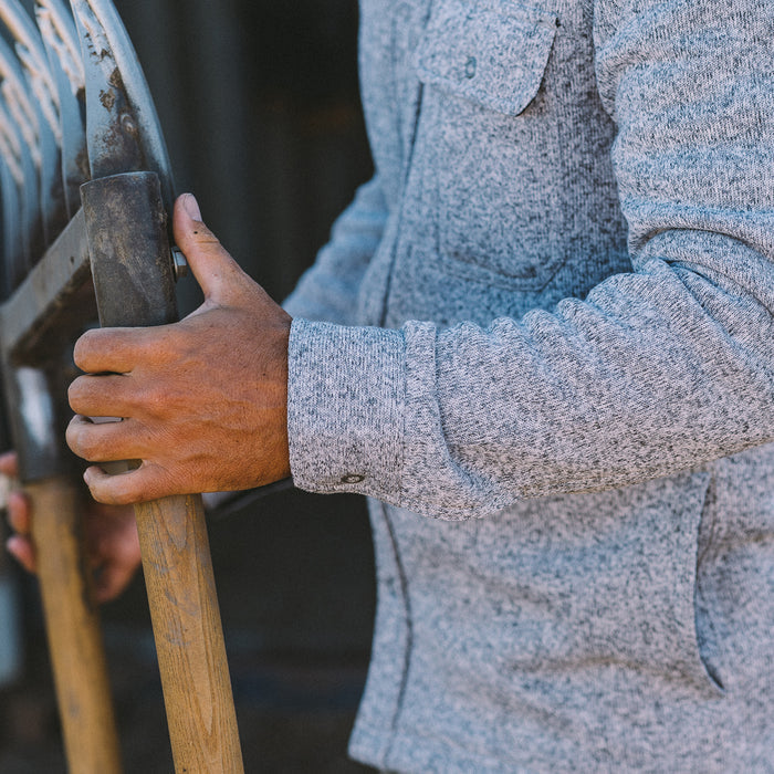 fit model wearing The Breaker Overshirt in Ash while holding a rake