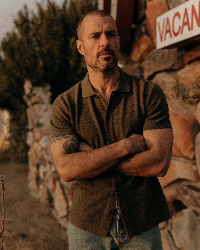 fit model with his arms crossed wearing The Button Down Polo in Cilantro Herringbone