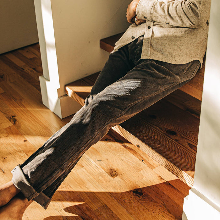 our fit model wearing The Camp Pant in Charcoal Corduroy—cropped shot, sitting on stairs