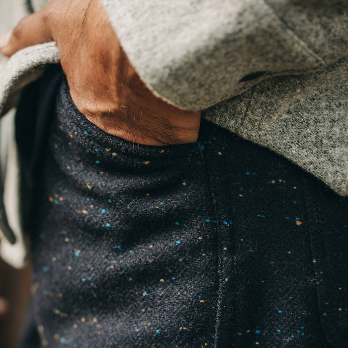 our fit model wearing The Camp Pant in Navy Donegal Herringbone—standing near shed, cropped shot, hand in pocket