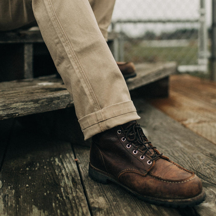 fit model sitting on wooden steps in The Camp Pant in Sand Boss Duck