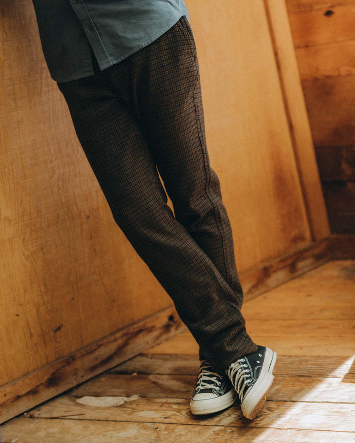 fit model leaning against the wall wearing The Carmel Pant in Timber Guncheck Italian Wool