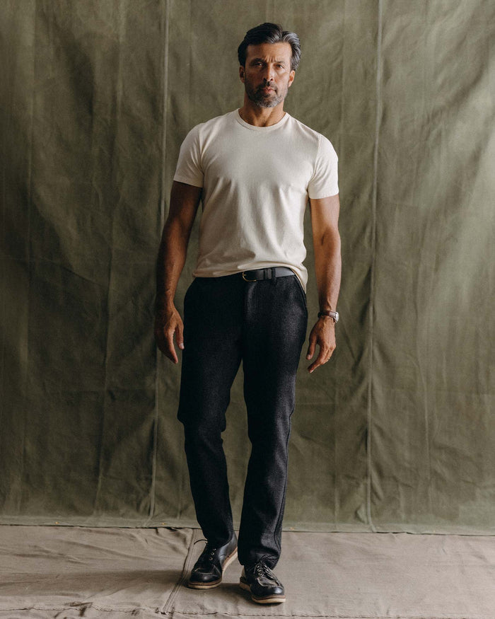 fit model leaning against the wall wearing The Carnegie Pant in Heather Charcoal Wool