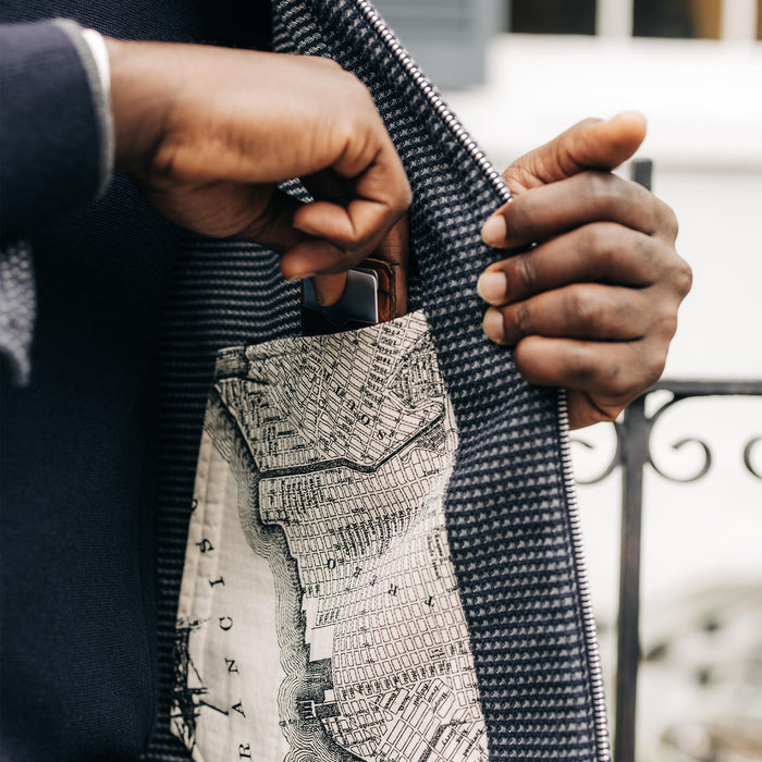 fit model putting a card case into the interior pocket on The Cavern Jacket in Navy Dobby Grid