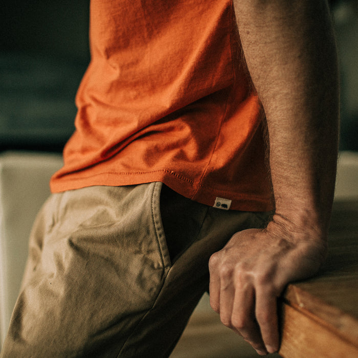 fit model leaning against a wooden table in The Cotton Hemp Tee in Monarch