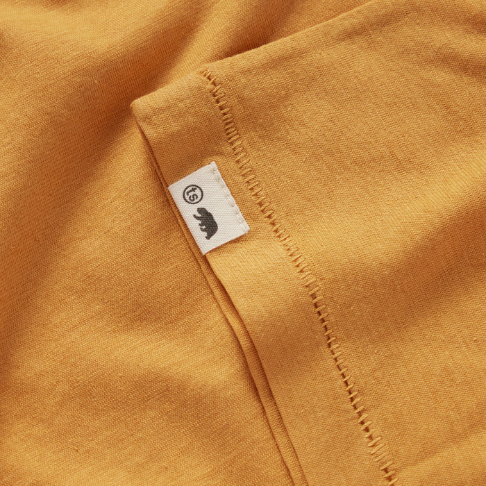 material shot of the TS tag on the sleeve of The Cotton Hemp Tee in Mustard