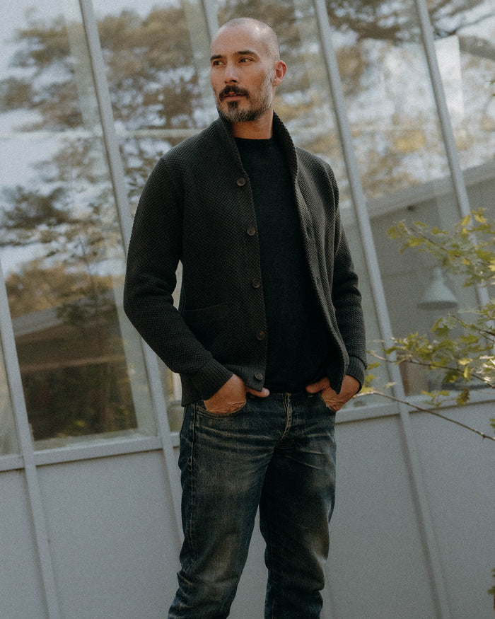 fit model sitting in The Crawford Cardigan Sweater in Charcoal