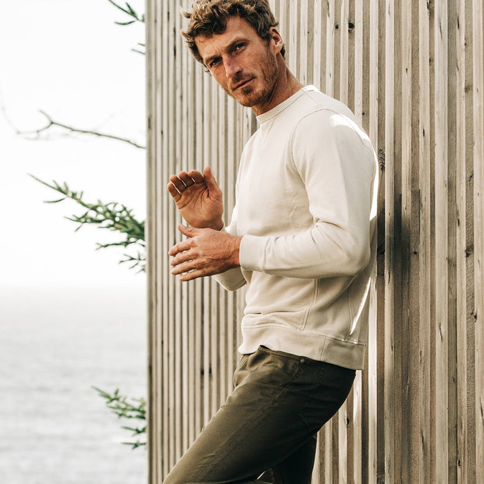 fit model wearing The Crewneck in Aluminum Terry, leaning against fence