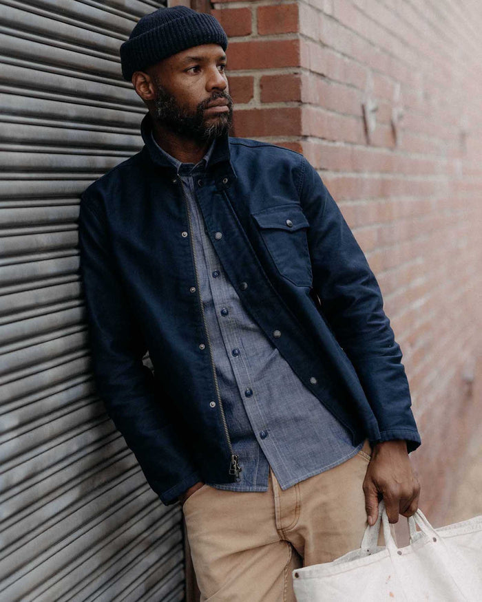 fit model leaning against the wall wearing The Deck Jacket in Dark Navy Bedford Cord
