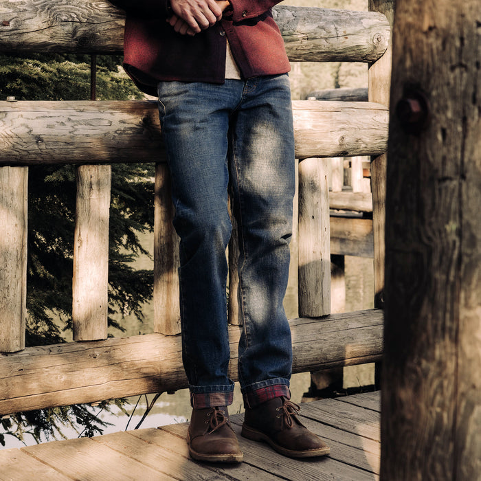 fit model leaning against a fence wearing The Democratic Brushed Back Jean in Sawyer Wash Organic Selvage