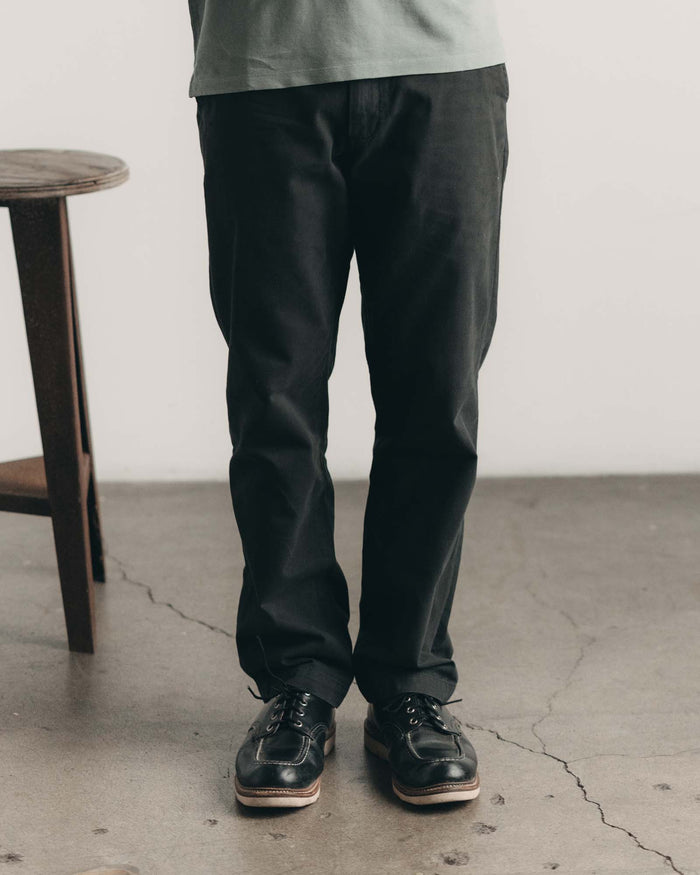 fit model with his hand in his pocket wearing The Democratic Foundation Pant in Organic Faded Black