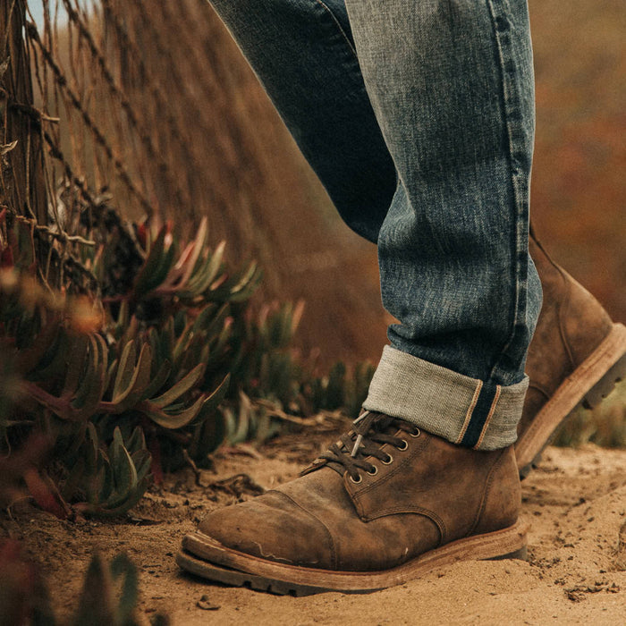 fit model wearing The Democratic Jean in in 18 Month Wash Organic Selvage, cuffed with boots