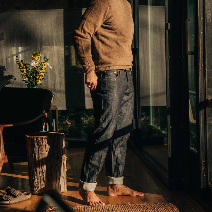 our fit model wearing The Democratic Everyday Jean—standing indoors looking right