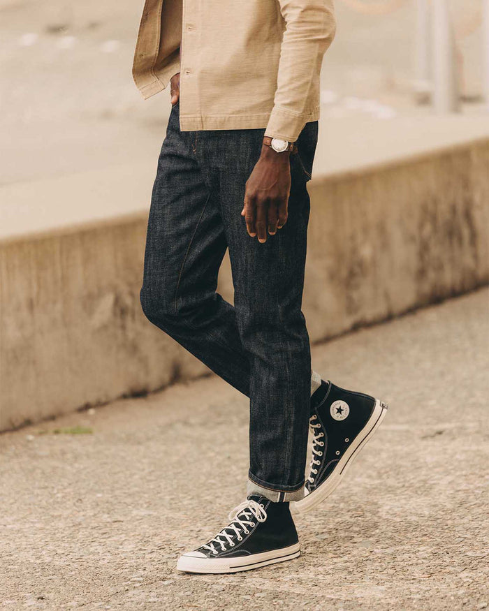 fit model leaning against the wall wearing The Democratic Jean in Rigid Organic Selvedge