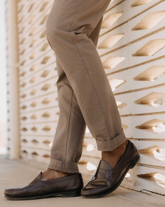 fit model leaning against the wall wearing The Easy Pant in Canteen Seersucker