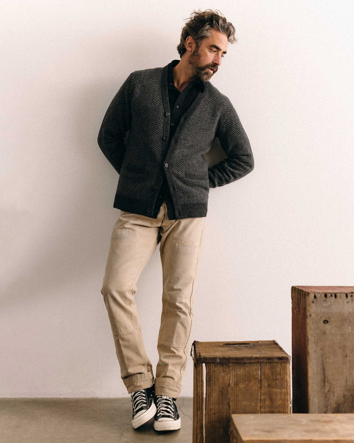 fit model leaning against a wall wearing The Eddy Cardigan in Heather Charcoal Herringbone