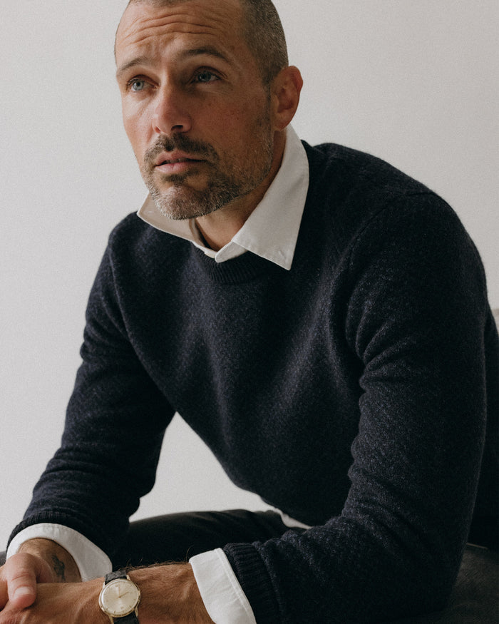 fit model sitting wearing The Eddy Crew in Heather Marine Herringbone