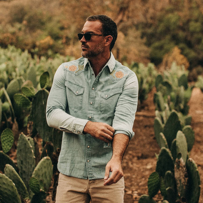 fit model wearing The Embroidered Western Shirt in Washed Denim, cuffing sleeve