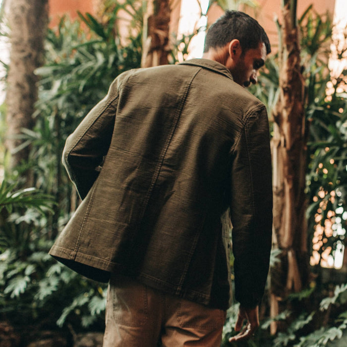 fit model wearing The Emerson Jacket in Olive Double Cloth, back shot near plants