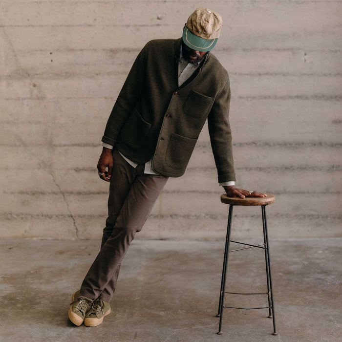 fit model leaning against a stool wearing The Evans Blazer in Forest Birdseye Wool