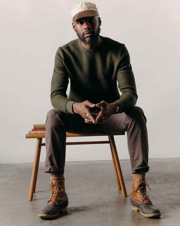 fit model sitting wearing The Evans Crew in Forest Birdseye Wool