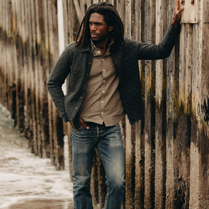 fit model leaning against the wall wearing The Fall Line Overshirt in Heather Coal Quilted Jersey