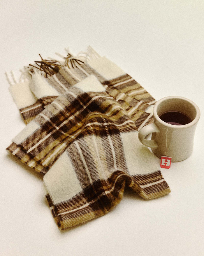 editorial flatlay of The Fireside Scarf in Butterscotch Plaid next to a cup of tea
