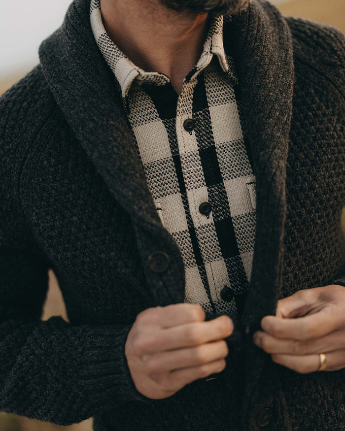 fit model buttoning up The Fisherman Shawl Cardigan in Heather Coal Merino