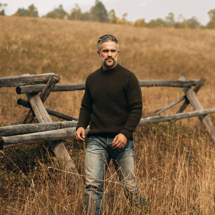 fit model wearing The Fisherman Sweater in Loden, walking in field