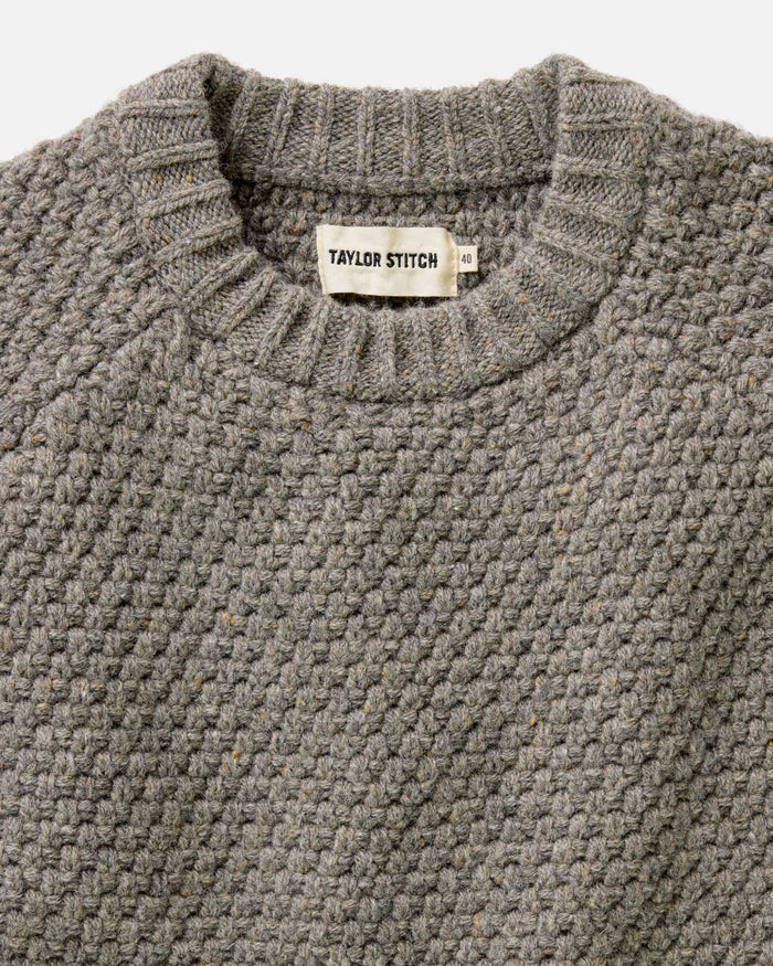 fit model standing on a boat wearing The Fisherman Sweater in Taupe Merino