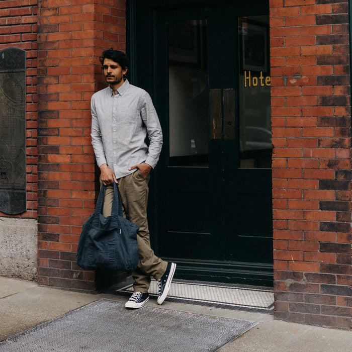 fit model leaning against the wall wearing The Foundation Tote in Organic Navy