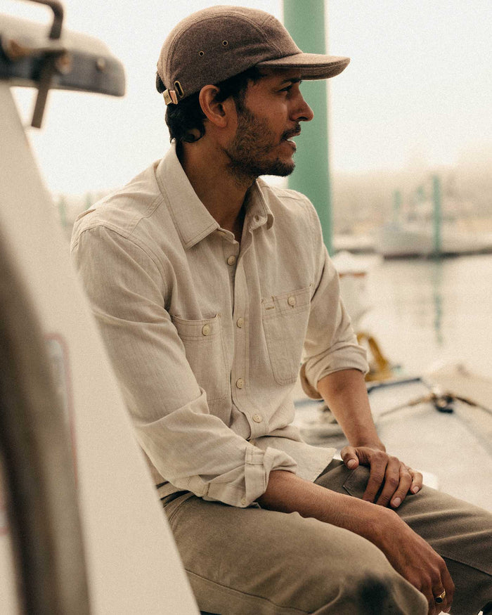 fit model sitting wearing The Foundry Shirt in Natural Chambray