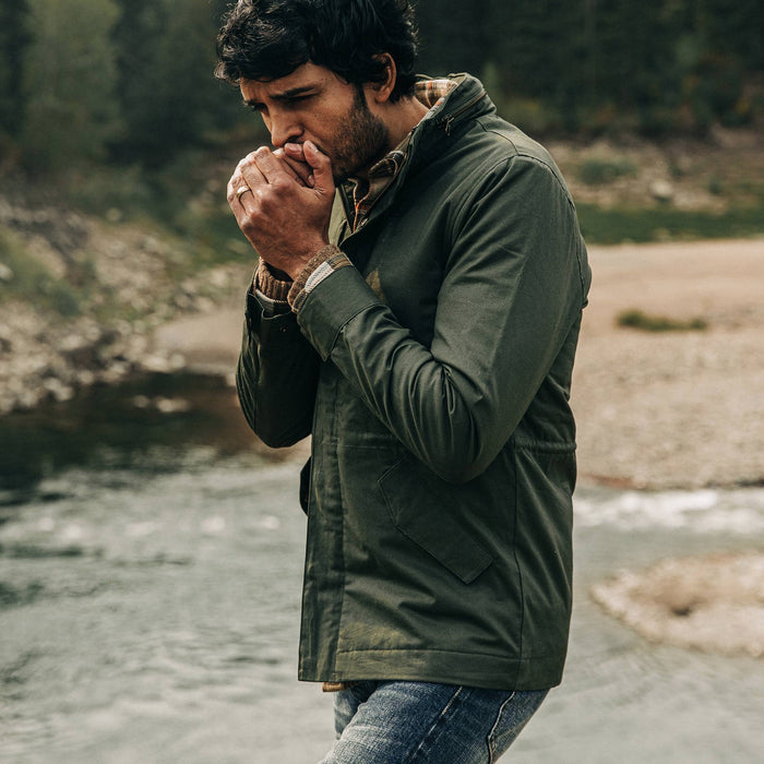 our fit model wearing The Harris Jacket in Forest Dry Wax—walking near creek