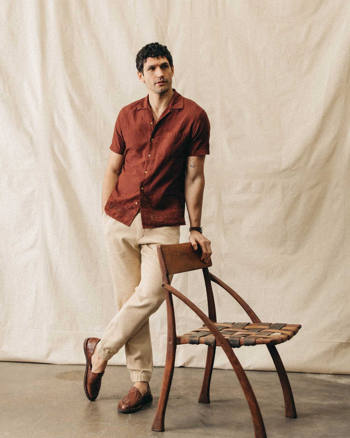 fit model leaning against a chair wearing The Hawthorne Shirt in Red Wine Border Eyelet