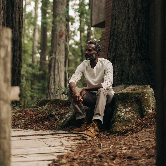 fit model sitting on a log in The Heavy Bag Henley in Natural