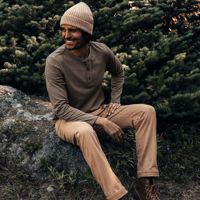 fit model sitting on a rock wearing The Heavy Bag Henley in Walnut