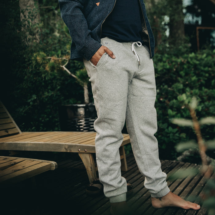 our fit model wearing The Heavy Bag Pant in Heather Grey Fleece with both hands in pocket on a deck