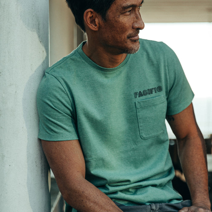 fit model rocking The Heavy Bag Tee in Pacific, sitting on porch, looking right