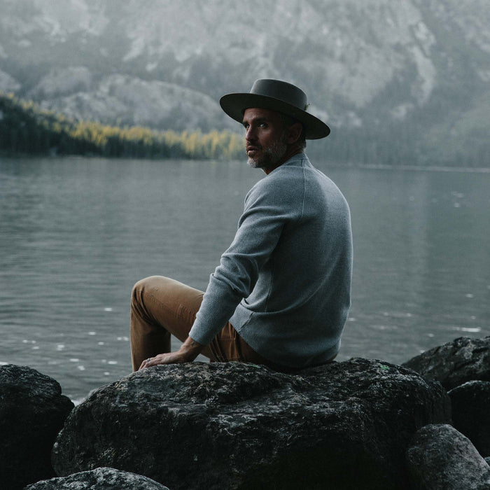 fit model sitting on a rock in The Heavy Bag Waffle Crewneck in Aluminum